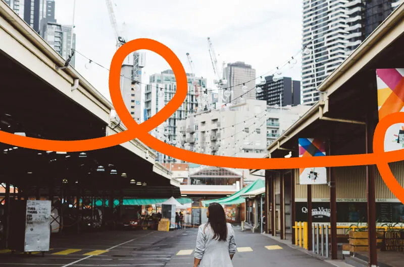 Photo of the back of a woman walking through the Queen Victoria Markets in Melbourne